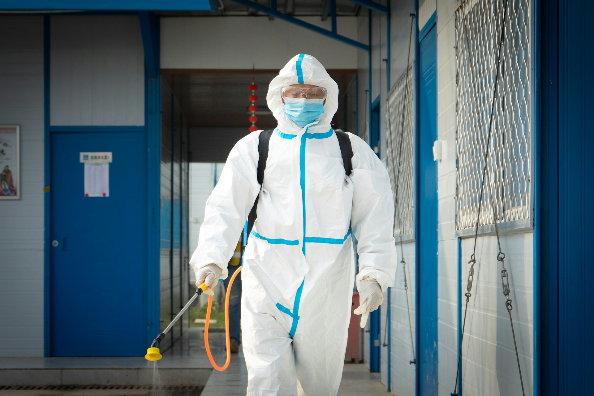 Person in personal protective gear wearing backpack sprayer