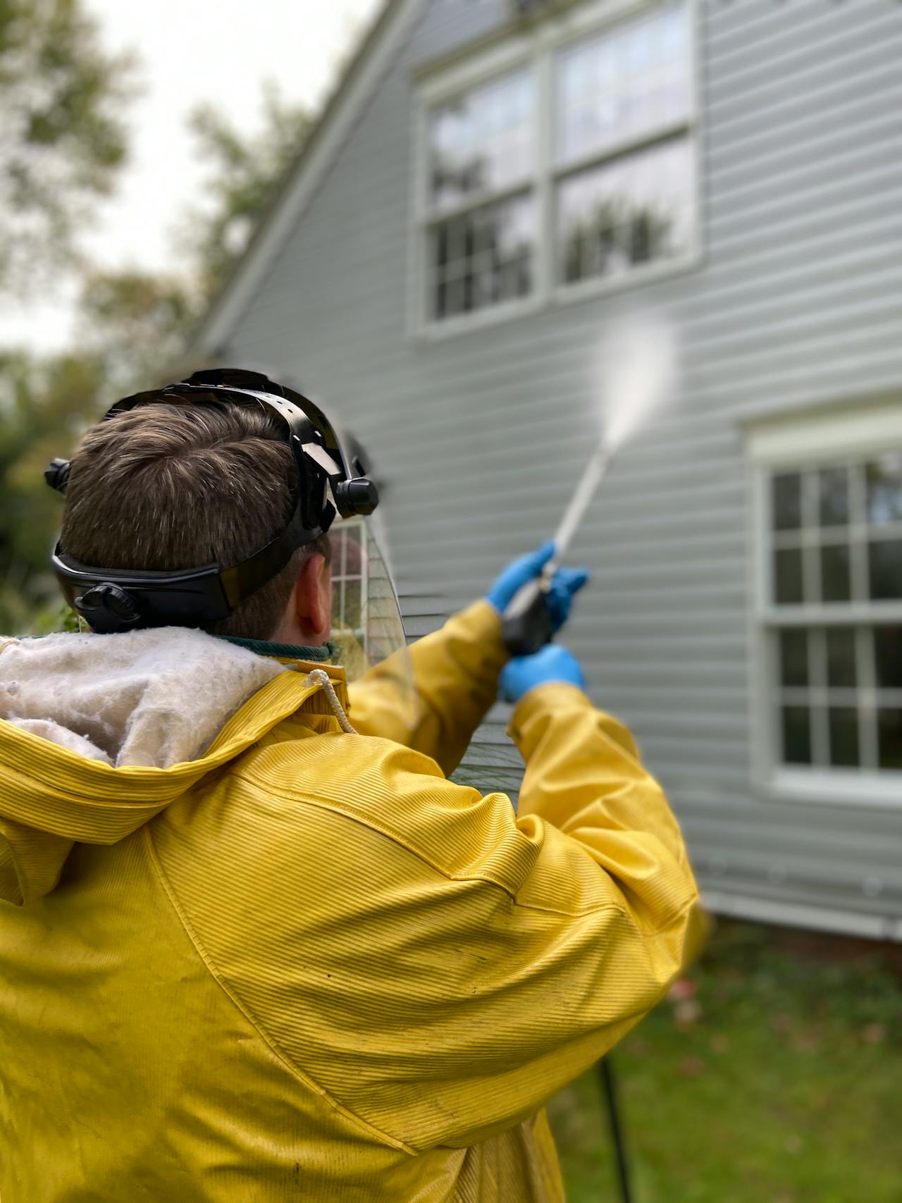 A person power washing a house.